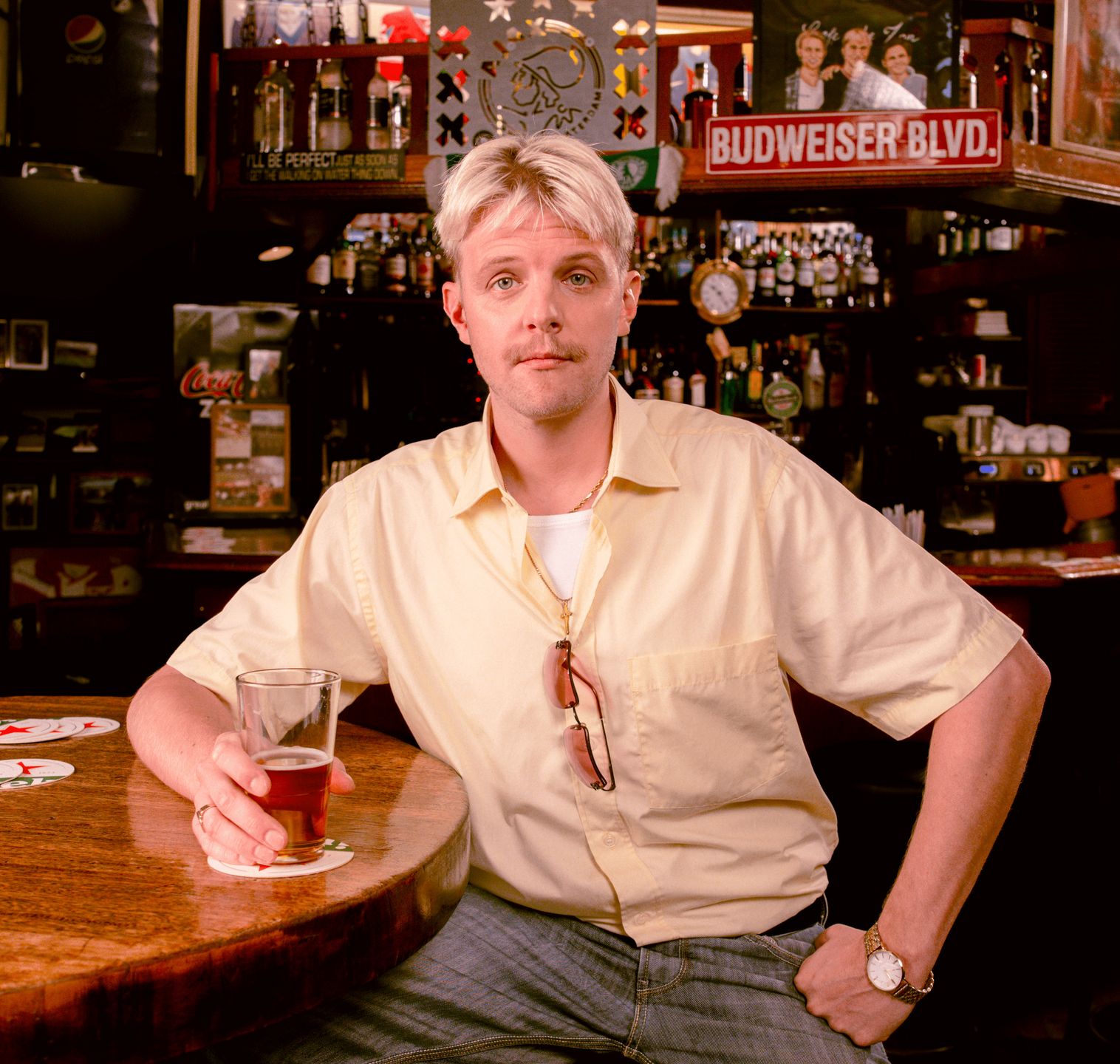 Campagnefoto van Jim Deddes, zittend aan een tafel in een café met een glas bier in zijn hand