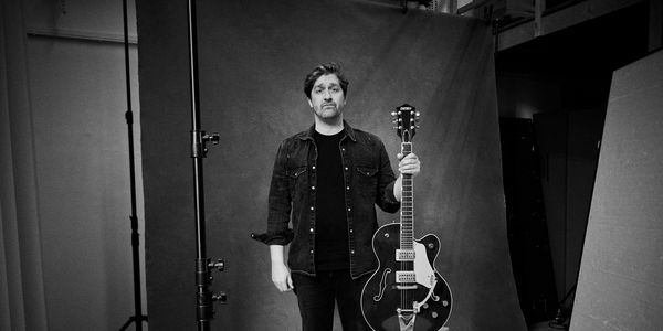 Zwart-wit foto van Alex Ploeg met een gitaar in zijn handen