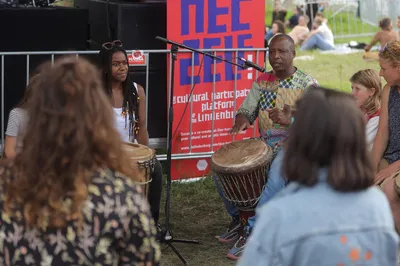 Twee muzikanten geven een djembéworkshop voor een groep festivalbezoekers.