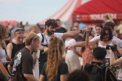 Festivalbezoekers die in een cirkel dansen en elkaars handen vasthouden.