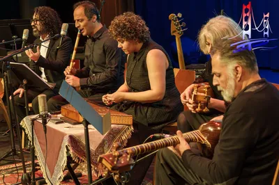 Groep muzikanten speelt traditionele instrumenten op het podium.