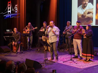 Zanger en band treden live op voor een theaterpubliek.