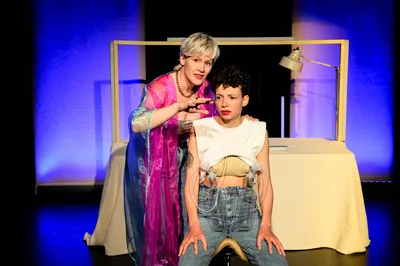 Twee personen in beeld: de een zit teneergeslagen op een kruk, terwijl de andere hoopvol opkijkt.