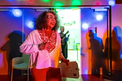 Vrouw in felgekleurde lichtval bij de ingang van de dansruimte