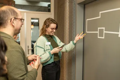 Volwassen deelnemers doen enthousiast mee aan een speelse opdracht met gekleurde stickers