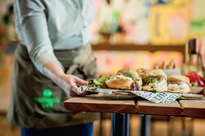 De kok van de Lindenberg zet een grote schaal met belegde broodjes op tafel