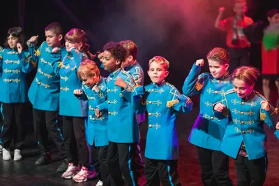 Kinderen in blauwe uniformen voeren een dans uit op het podium