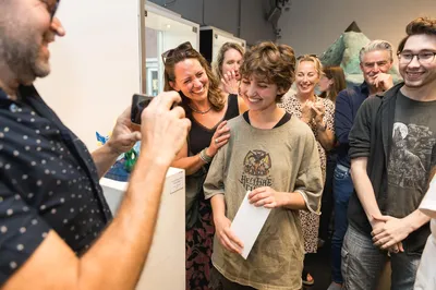 Jongere wordt gefotografeerd terwijl een groep trots toekijkt