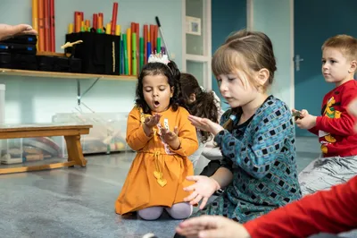 Jonge kinderen zitten op de vloer en ontdekken muziek- of ritme-materiaal tijdens een workshop