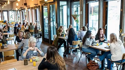 Het Lindenberg Cafe waarin mensen aan tafels zitten te lunchen.