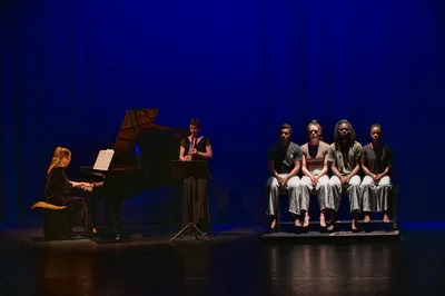 Pianist en klarinettist spelen terwijl vier dansers naast elkaar op een bank zitten.