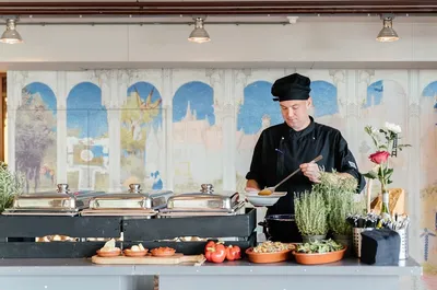 De kok van de Lindenberg achter een buffet met serveerschalen en kruidenplantjes op de voorgrond