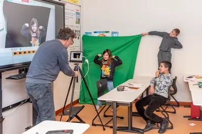 Kinderen maken een greenscreen-video in de klas met hulp van een docent
