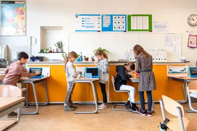 Leerlingen werken geconcentreerd aan een opdracht met tablets en knutselmaterialen