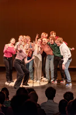 Leerlingen maken lachend een selfie tijdens een feestelijk moment op het podium