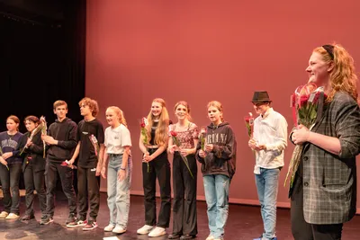 Jonge spelers staan in een rij op het podium en ontvangen trots een roos