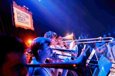Een ingezoomde foto's op de blazers van het orkest, boven hen hangt een bordje met de tekst "Van eigen bodem".