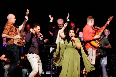 Een zingende man en een vrouw worden enthousiast begeleid door een band.