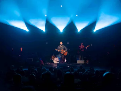 Peter van Rooijen staat met een band op een verlicht podium.