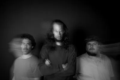 De drie mannen van de band kijken zeer doordringend de camera in, door een effect is hun beweging nog wazig langs hen heen te zien.