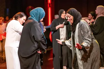 Twee vrouwen in lange jurken dansen tegenover elkaar, omringd door andere dansende bezoekers in een warme, sfeervolle zaal