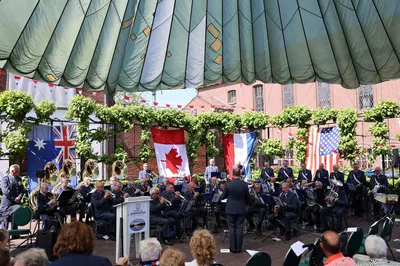 Een band speelt buiten op een plein. In de lucht hangen vlaggen van verschillende landen in de lucht.