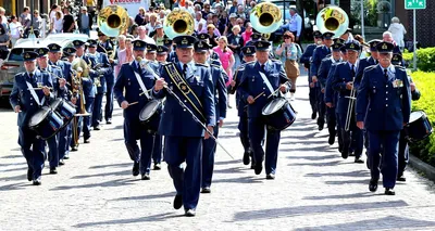 Een fanfare loopt spelend de camera tegemoet. Achteraan lopen mensen enthousiast met hen mee.