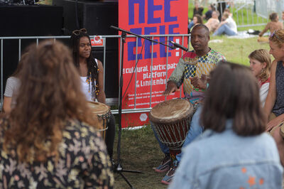 Twee muzikanten geven een djembéworkshop voor een groep festivalbezoekers.