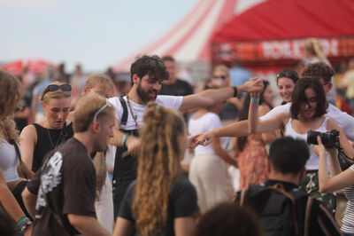 Festivalbezoekers die in een cirkel dansen en elkaars handen vasthouden.