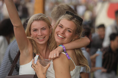 Twee jonge vrouwen lachen en omhelzen elkaar op een festival.