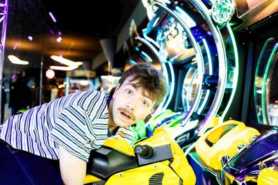 Een jongen staat voor een casino-automaat en kijkt geschokt naar rechts, recht de camera in.