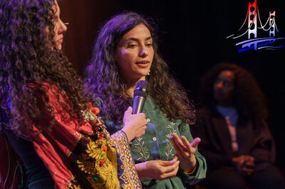 Vrouw spreekt in een microfoon tijdens een podiumgesprek.