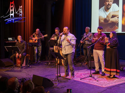 Zanger en band treden live op voor een theaterpubliek.