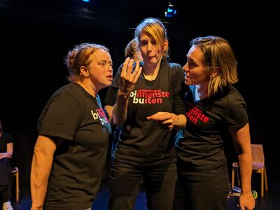 Drie vrouwen staan dicht bij elkaar in een theatraal improvisatiespel.