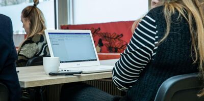 Een vrouw met lang haar zit achter een laptop te typen