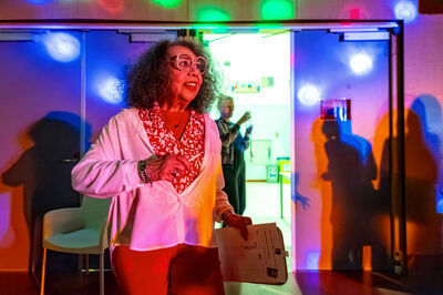 Vrouw in felgekleurde lichtval bij de ingang van de dansruimte