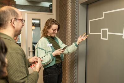 Volwassen deelnemers doen enthousiast mee aan een speelse opdracht met gekleurde stickers