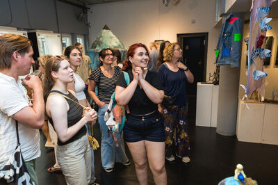 Groep bezoekers bekijkt kunstwerken in een galerie en reageert enthousiast