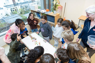 Een groep kinderen werkt nieuwsgierig samen aan een kleurrijke knutselopdracht