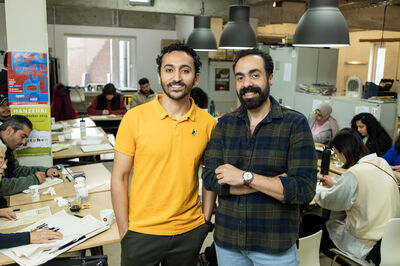 Twee docenten staan glimlachend in een lesruimte waar cursisten geconcentreerd tekenen.