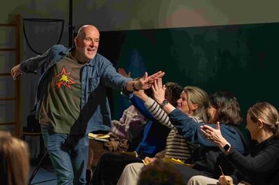 Een man loopt langs zijn publiek en geeft enthousiast een high-five.