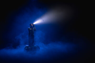 Een man kijkt in de mist met een schijnwerper de verte in