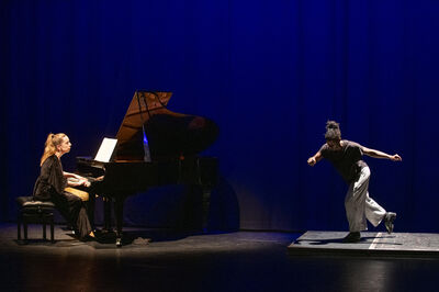 Pianist speelt terwijl een danser solo danst op een klein verhoogd vlak.