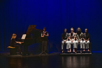 Pianist en klarinettist spelen terwijl vier dansers naast elkaar op een bank zitten.