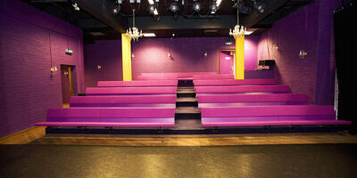 Een lege Karolingenzaal met roze banken en theaterbelichting.