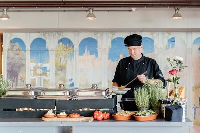 De kok van de Lindenberg achter een buffet met serveerschalen en kruidenplantjes op de voorgrond