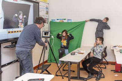 Kinderen maken een greenscreen-video in de klas met hulp van een docent