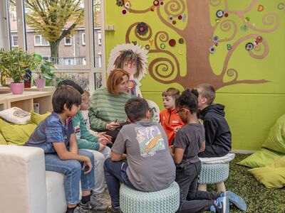 Kinderen zitten om een volwassene heen om te luisteren naar een verhaal