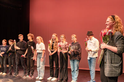 Jonge spelers staan in een rij op het podium en ontvangen trots een roos