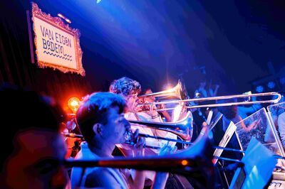 Een ingezoomde foto's op de blazers van het orkest, boven hen hangt een bordje met de tekst "Van eigen bodem".